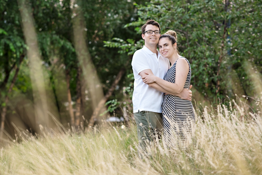 An engaged couple embrace in the long grass in the park in old city Philadelphia.